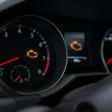 Cruscotto auto con spia motore accesa. Il simbolo giallo indica un problema da controllare.