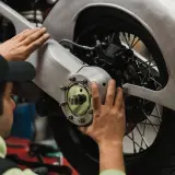 Meccanico effettua il primo tagliando moto, controllando il mozzo posteriore e il freno.
