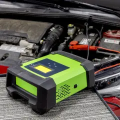 Carrozzeria rossa con cofano aperto, motore e batteria. Un caricabatterie verde è collegato per risolvere la batteria scarica.