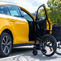 Auto gialla con portiera aperta e carrozzina accanto, simbolo di un nuovo inizio e del passaggio di proprietà auto acquistata con legge 104.
