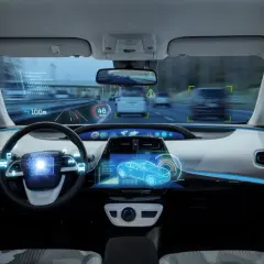 Interno di un'auto con display olografico che mostra dati di guida assistita, velocità e navigazione.