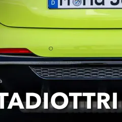 Guida: cosa sono i catadiottri? Riflettori rossi posteriori su un'auto verde brillante, essenziali per la sicurezza.