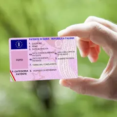 Mano che mostra una patente di guida italiana. Il numero di patente è visibile, con il codice patente 71 che indica la categoria.