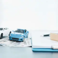 Modellini di auto su banconote, con penna e timbro su documenti. Pensando a disdetta assicurazione auto quanto tempo prima.