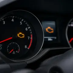 Cruscotto auto con spia motore accesa. Il simbolo giallo indica un problema da controllare.