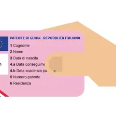 Una mano tiene una patente di guida italiana, un documento essenziale per la circolazione, che a volte non è duplicabile.