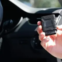 Una mano tiene una scatola nera macchina, un dispositivo tecnologico per monitorare le prestazioni del veicolo.