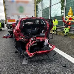 Un'auto rossa gravemente danneggiata dopo un incidente. Sul posto un'ambulanza e i vigili del fuoco. Ecco cosa fare in caso di incidente.