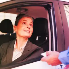 Donna in auto riceve un documento, forse per l'assicurazione dopo scadenza.