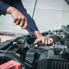 Meccanico con chiave inglese lavora sul motore, assicurando il tagliando obbligatorio per la sicurezza.