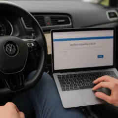 Controllo RCA tramite banca dati ANIA targhe, con laptop sul volante.