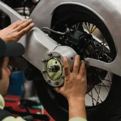 Meccanico effettua il primo tagliando moto, controllando il mozzo posteriore e il freno.