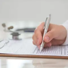 Medico compila modulo per la validità certificato medico patente b. Stetoscopio sullo sfondo.