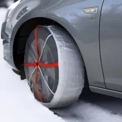 Auto grigia su neve con calze da neve omologate montate su una ruota. Sicurezza invernale garantita.