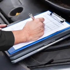 Un meccanico controlla il libretto per sapere tagliando auto ogni quanto va fatto.