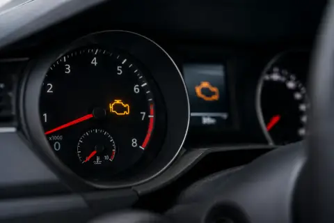 Cruscotto auto con spia motore accesa. Il simbolo giallo indica un problema da controllare.