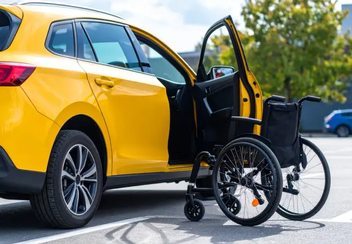 Auto gialla con portiera aperta e carrozzina accanto, simbolo di un nuovo inizio e del passaggio di proprietà auto acquistata con legge 104.