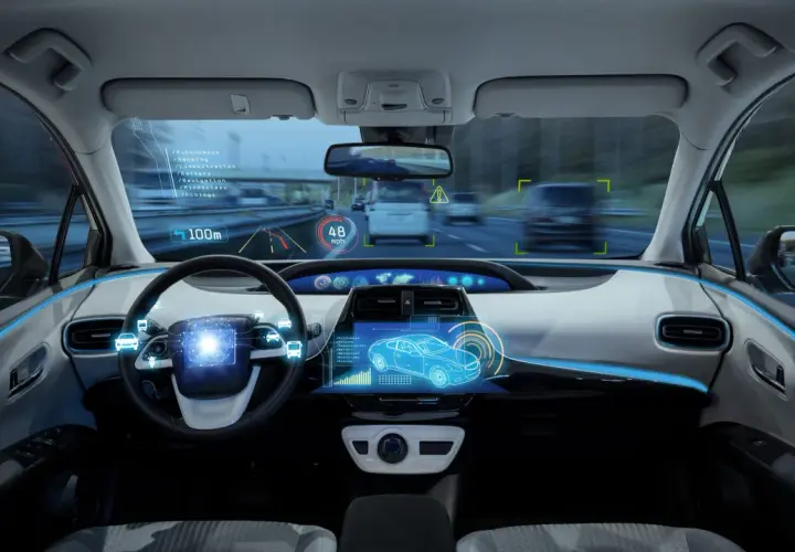 Interno di un'auto con display olografico che mostra dati di guida assistita, velocità e navigazione.
