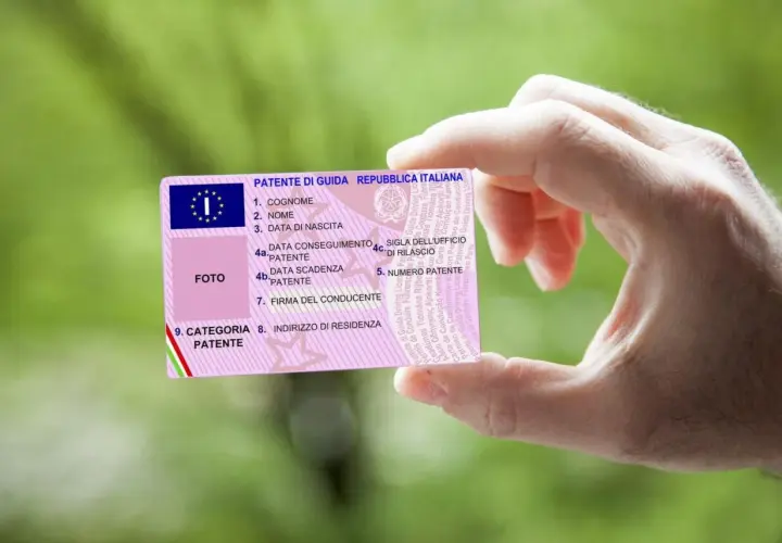 Mano che mostra una patente di guida italiana. Il numero di patente è visibile, con il codice patente 71 che indica la categoria.