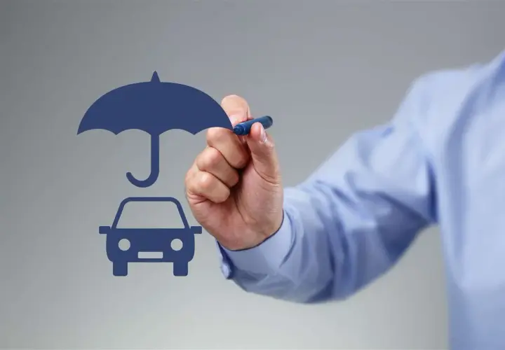 Un uomo disegna un'auto sotto un ombrello, simbolo di protezione. Si può cambiare assicurazione prima della scadenza annuale.