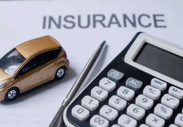 Modellino auto dorata su foglio "INSURANCE", calcolatrice e penna. L'auto intestata al figlio, l'assicurazione al padre.