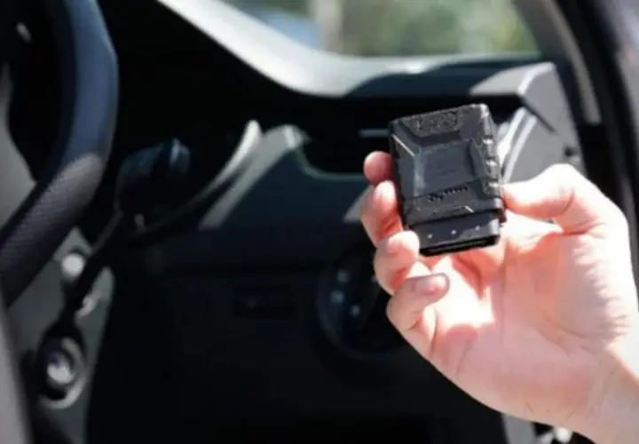 Una mano tiene una scatola nera macchina, un dispositivo tecnologico per monitorare le prestazioni del veicolo.