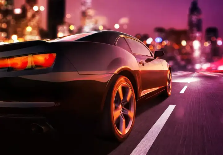Auto sportiva di notte in città. Pensando a quando si paga il superbollo, la strada si illumina di luci sfocate.