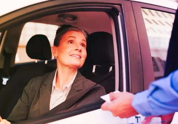 Donna in auto riceve un documento, forse per l'assicurazione dopo scadenza.
