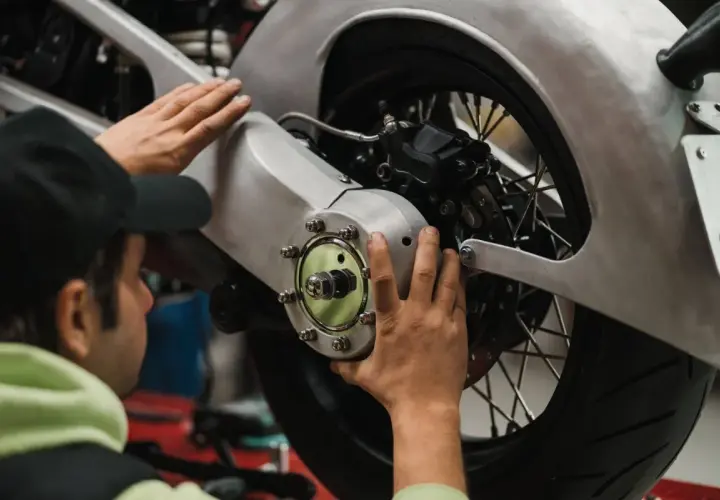 Meccanico effettua il primo tagliando moto, controllando il mozzo posteriore e il freno.