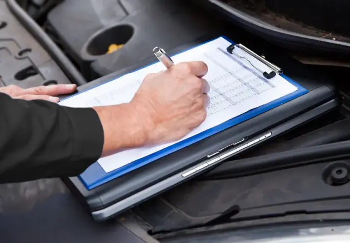 Un meccanico controlla il libretto per sapere tagliando auto ogni quanto va fatto.