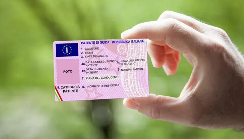 Mano che mostra una patente di guida italiana. Il numero di patente è visibile, con il codice patente 71 che indica la categoria.