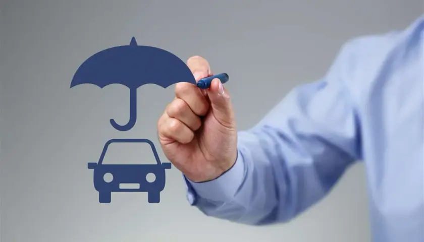 Un uomo disegna un'auto sotto un ombrello, simbolo di protezione. Si può cambiare assicurazione prima della scadenza annuale.