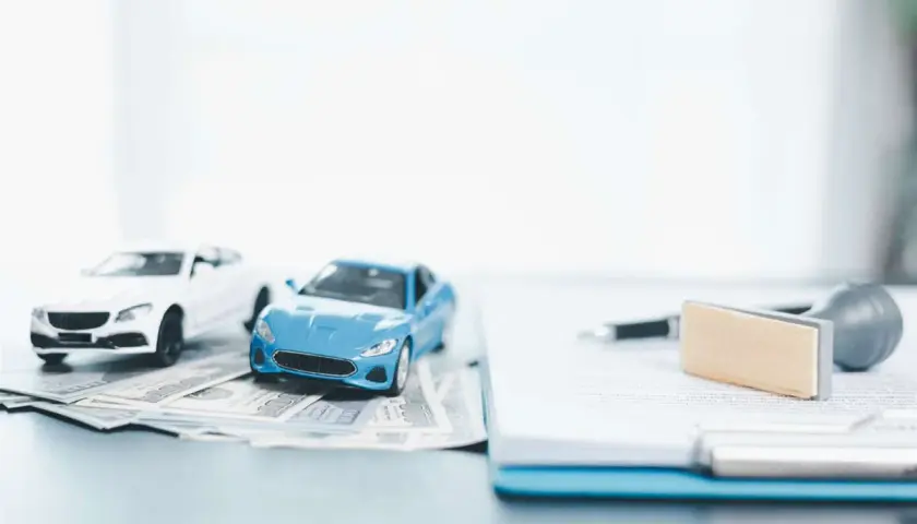 Modellini di auto su banconote, con penna e timbro su documenti. Pensando a disdetta assicurazione auto quanto tempo prima.