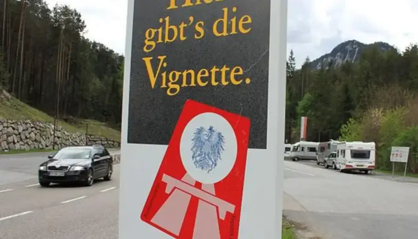 Cartello stradale "Qui si vende la Vignette" vicino al confine e61 Slovenia. Veicoli in transito e campeggiatori.
