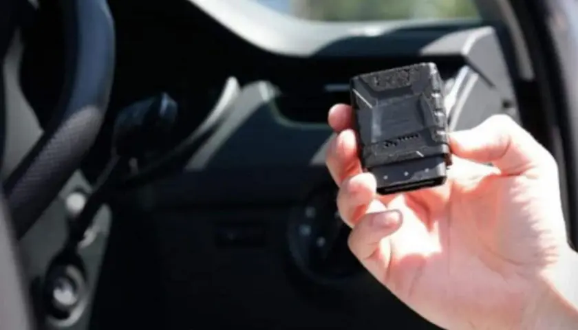 Una mano tiene una scatola nera macchina, un dispositivo tecnologico per monitorare le prestazioni del veicolo.