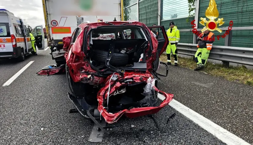 Un'auto rossa gravemente danneggiata dopo un incidente. Sul posto un'ambulanza e i vigili del fuoco. Ecco cosa fare in caso di incidente.