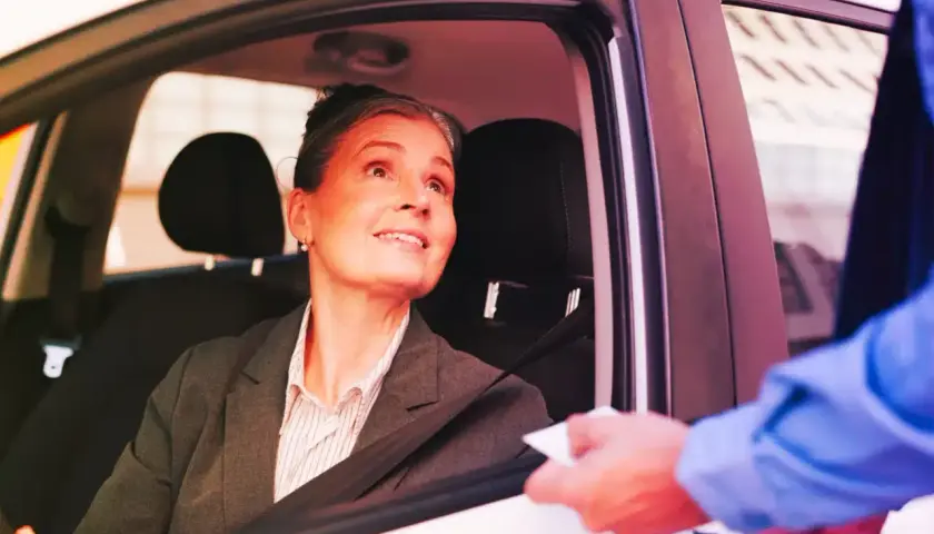 Donna in auto riceve un documento, forse per l'assicurazione dopo scadenza.