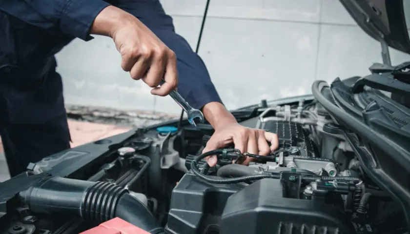 Meccanico con chiave inglese lavora sul motore, assicurando il tagliando obbligatorio per la sicurezza.