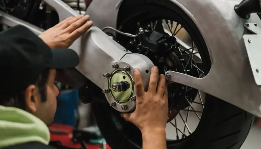 Meccanico effettua il primo tagliando moto, controllando il mozzo posteriore e il freno.