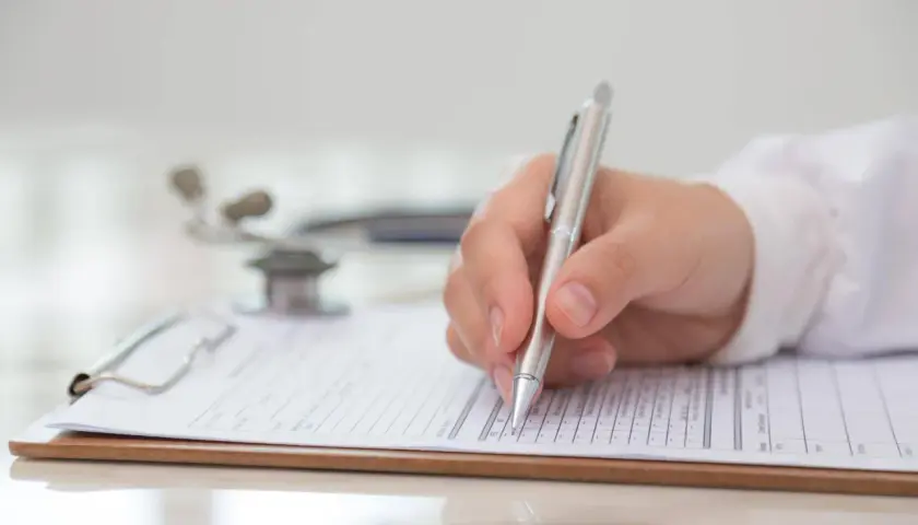 Medico compila modulo per la validità certificato medico patente b. Stetoscopio sullo sfondo.