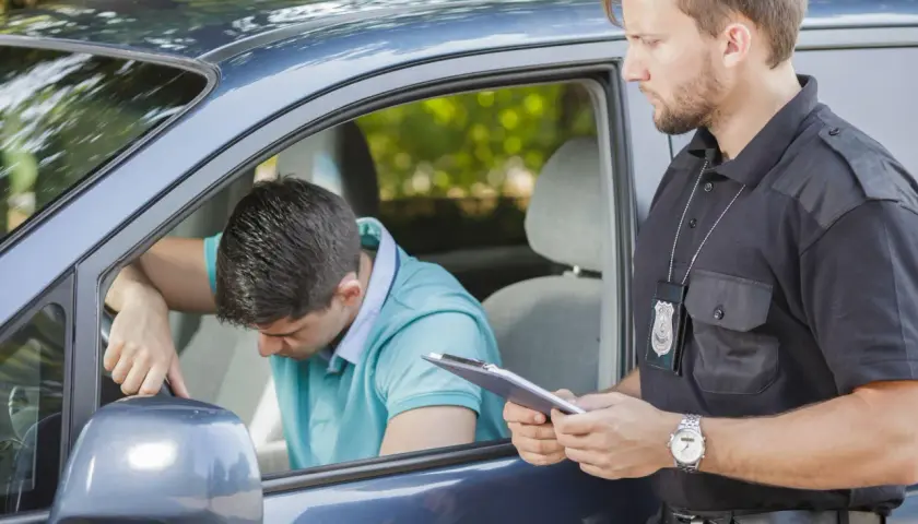 Agente di polizia parla con un automobilista, forse per evitare sospensione patente pagando una multa.