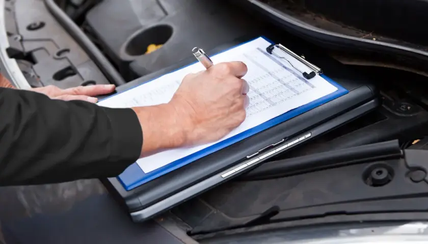 Un meccanico controlla il libretto per sapere tagliando auto ogni quanto va fatto.