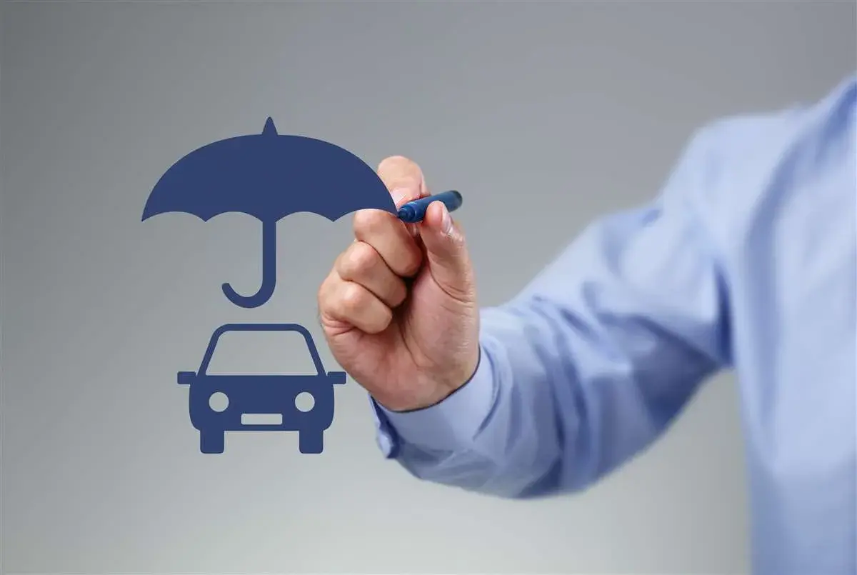 Un uomo disegna un'auto sotto un ombrello, simbolo di protezione. Si può cambiare assicurazione prima della scadenza annuale.