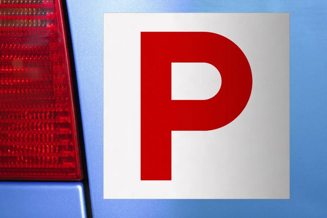 Targa "P" rossa su sfondo bianco, applicata su un'auto blu. Indica un neopatentato alla guida.