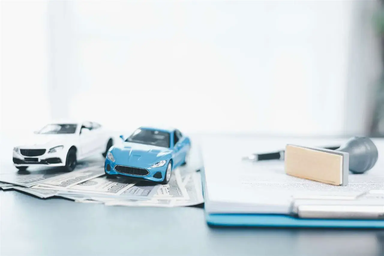 Modellini di auto su banconote, con penna e timbro su documenti. Pensando a disdetta assicurazione auto quanto tempo prima.