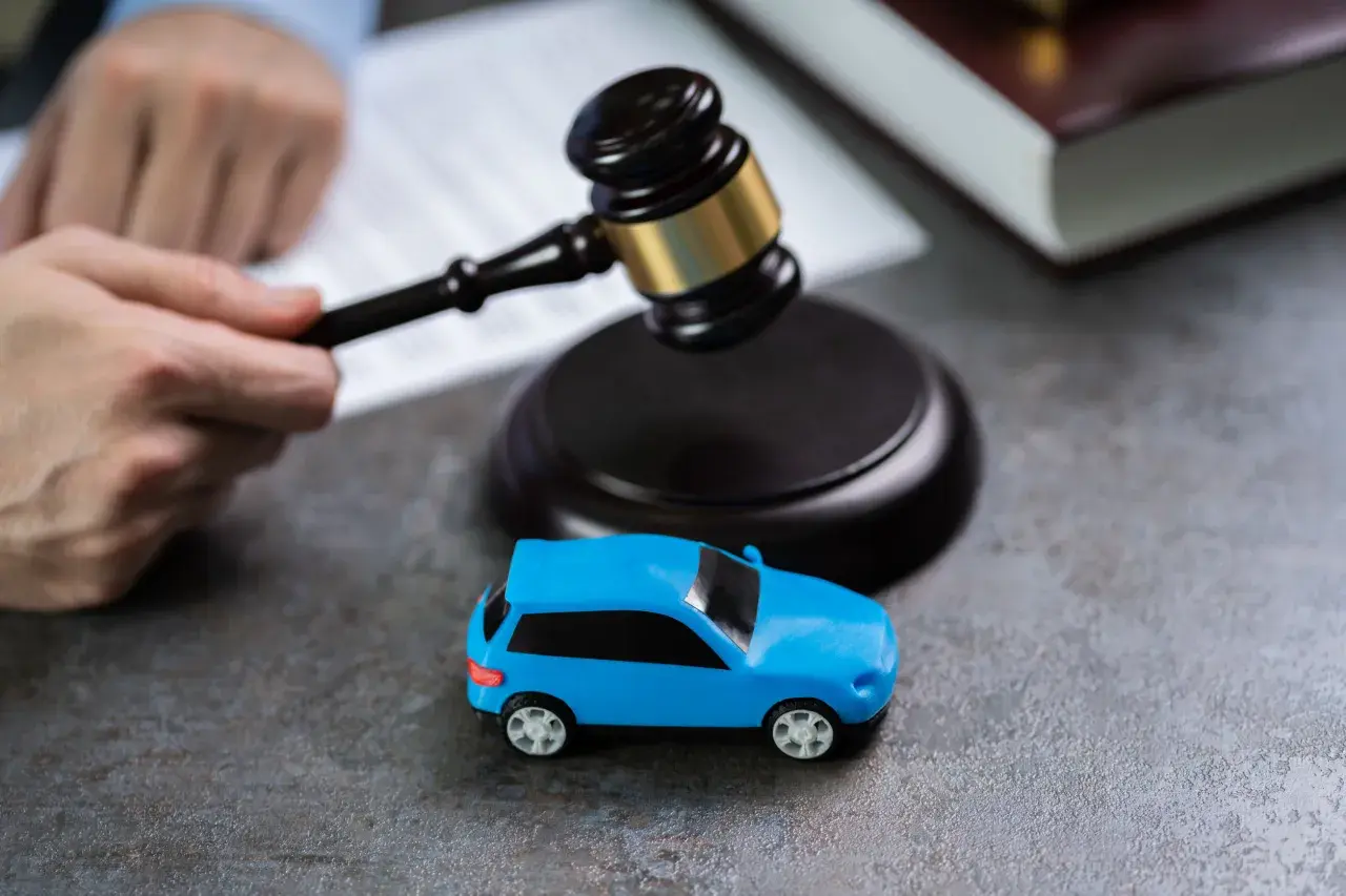 Martelletto da giudice vicino a un'auto blu giocattolo, suggerisce il costo della perdita di possesso in un contesto legale.