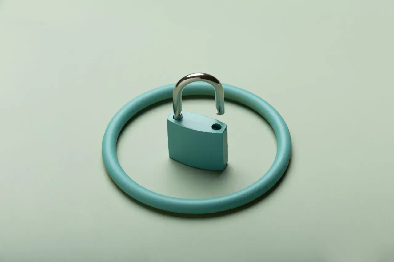 Un lucchetto aperto su un cerchio turchese, simbolo di accesso agli atti assicurazione e trasparenza.