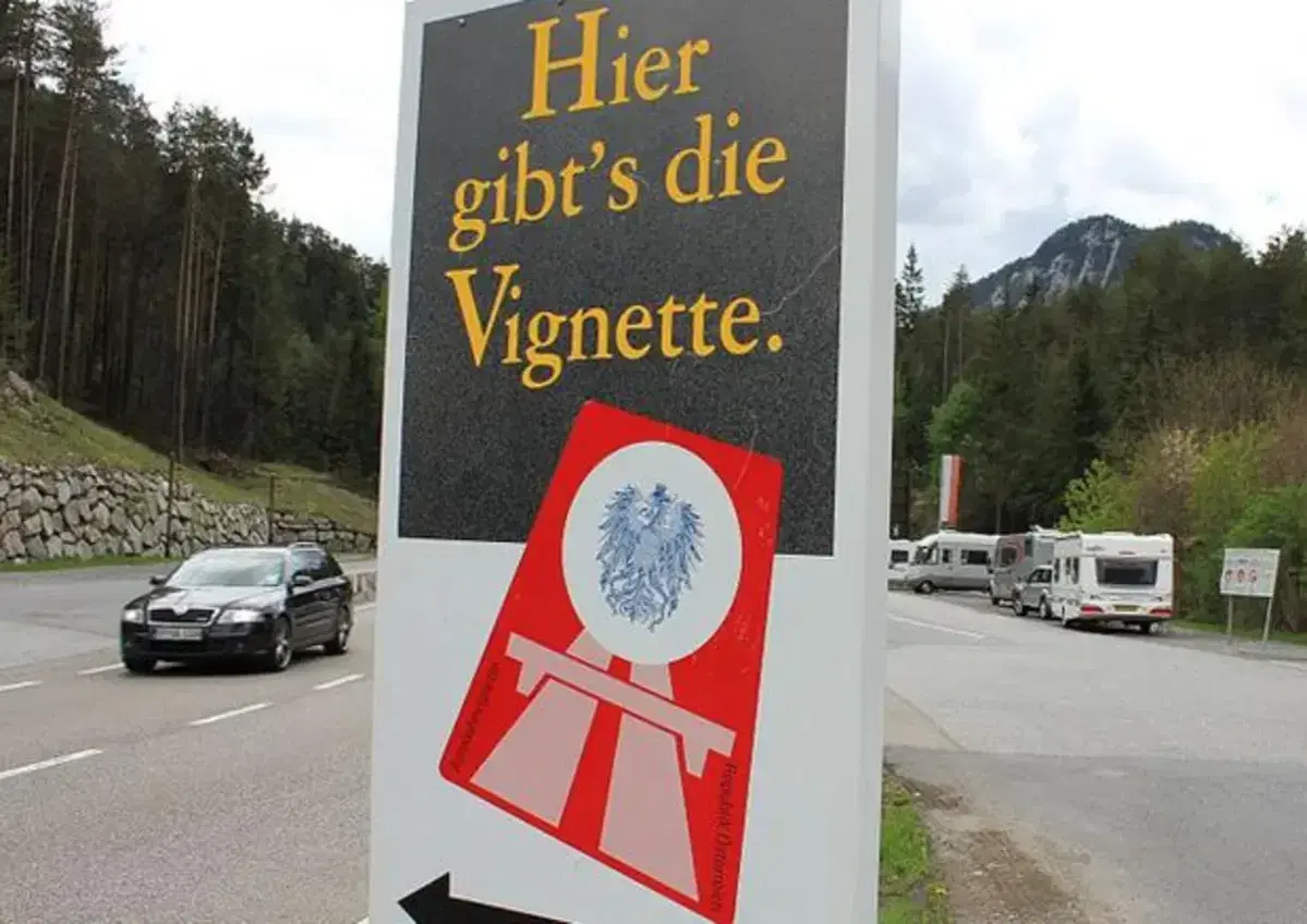 Cartello stradale "Qui si vende la Vignette" vicino al confine e61 Slovenia. Veicoli in transito e campeggiatori.