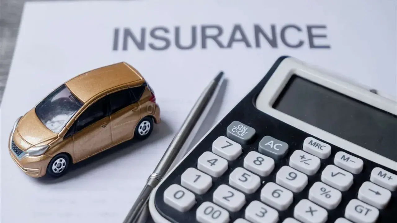 Modellino auto dorata su foglio "INSURANCE", calcolatrice e penna. L'auto intestata al figlio, l'assicurazione al padre.