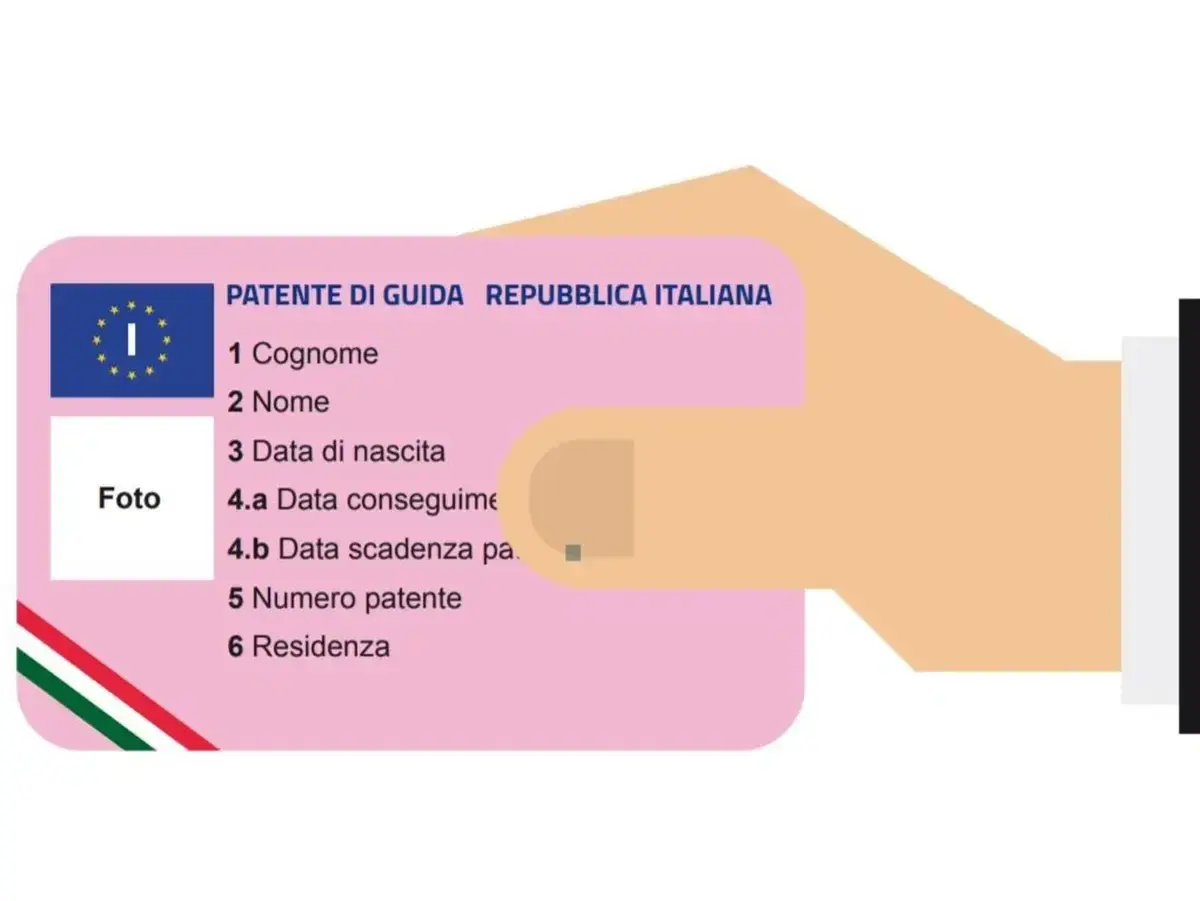 Una mano tiene una patente di guida italiana, un documento essenziale per la circolazione, che a volte non è duplicabile.
